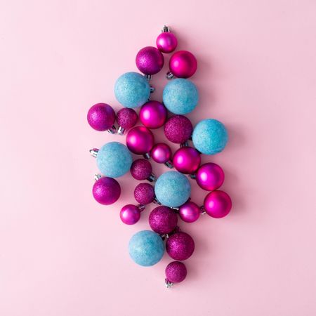 Arrangement of blue and pink festive baubles on pink background