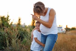 Pregnant mother point out something to her son standing in nature