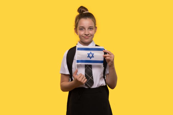 Schoolgirl proudly holds the Israeli flag while posing.