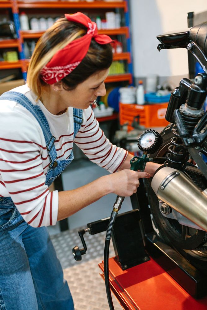Mechanic woman checking tire air pressure of motorcycle