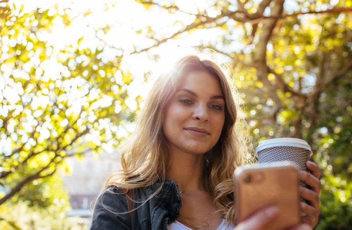 Woman clicking a selfie holding a takeaway coffee