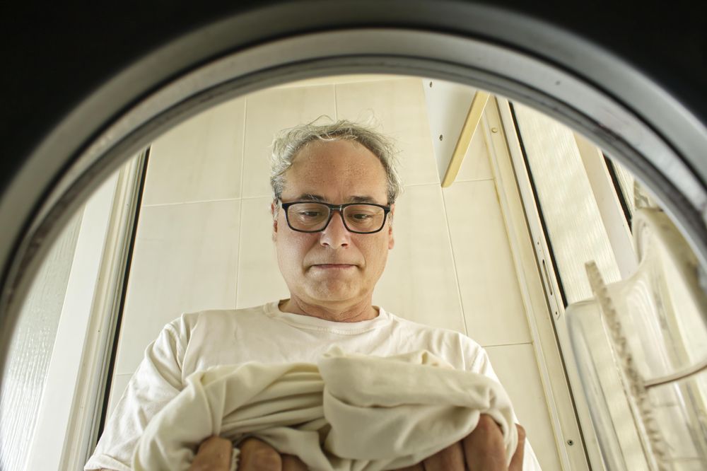 Man doing laundry seen from inside the washing machine