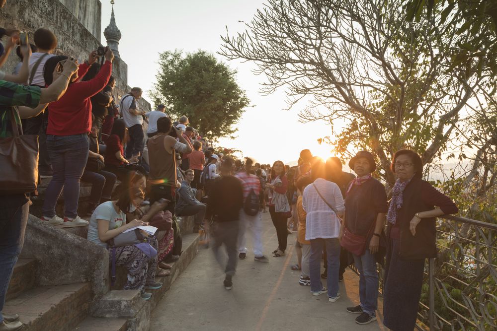 Luang Prabang, Laos - December 14, 2020: Crowds of tourists huddle atop the Phousi Hill viewpoint