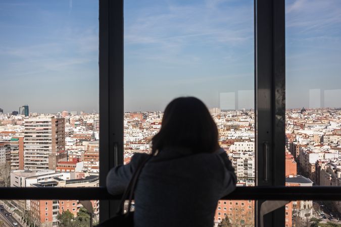 Anonymous woman looking out balcony window