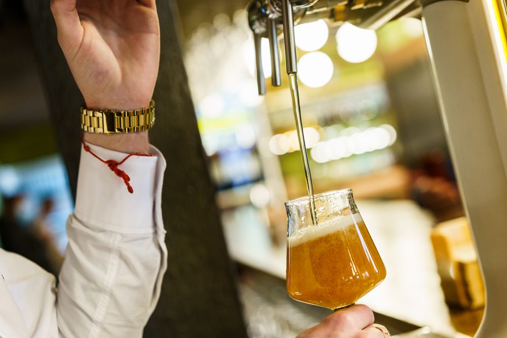 Closeup of bartender pouring pint into glassware