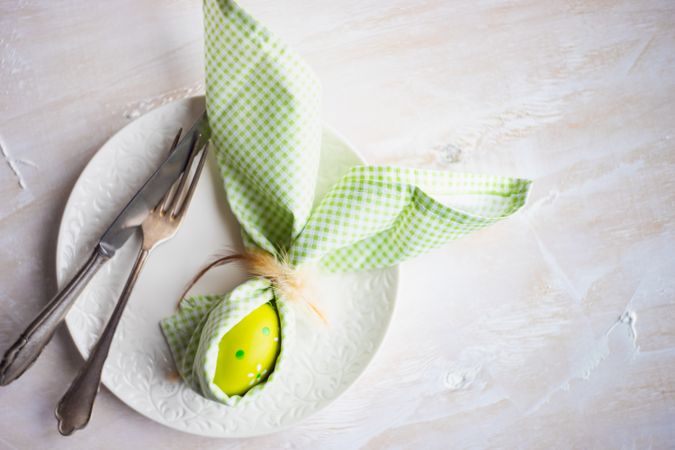 Easter holiday concept of green Easter egg wrapped with rabbit ears with napkin