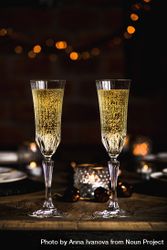 Two crystal flutes full of champagne on wooden table 4mgDo0