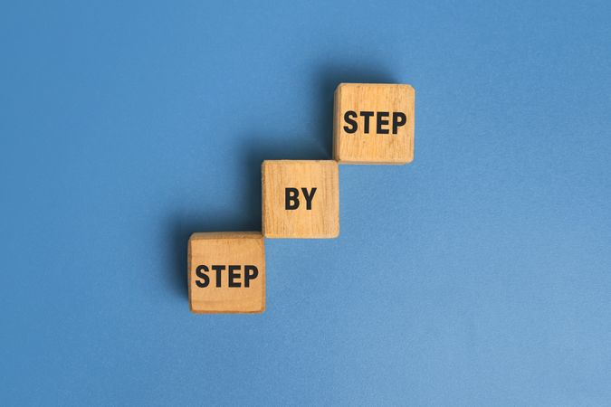 step by step word on wooden blocks staircase isolated on blue background. concept of success progress or career