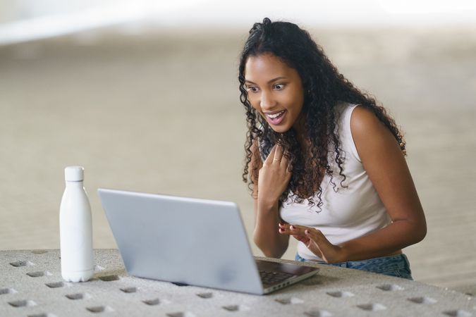 An Excited Young Woman Who is Engaged and Concentrated While Using a Laptop in a Modern Workspace