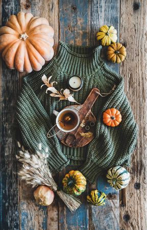 Flat-lay of dark green knitted sweater, and autumnal accessories, top view