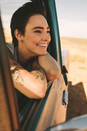 Close up of happy woman leaning out of window of classic truck on road trip