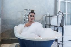 Woman taking foamy bath in a blue bathtub