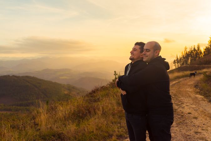 Men hugging on road on hill