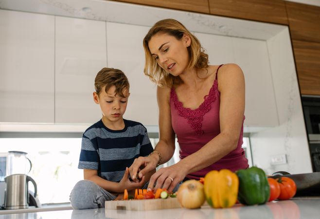 Woman with little boy cooking food at home