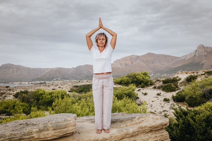 Barefoot woman meditating on stone