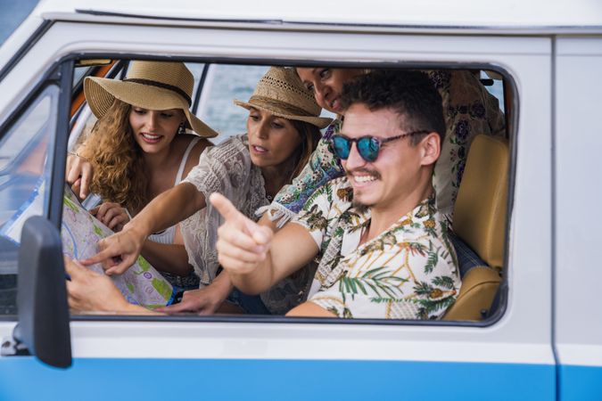 Group of women showing road on map in hands of man in car