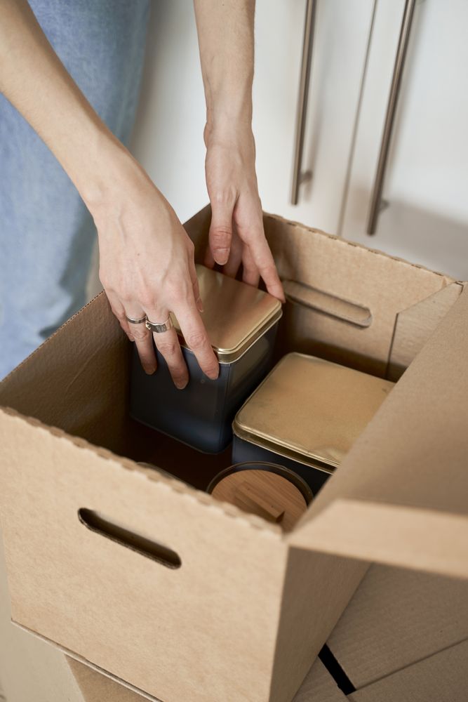 Anonymous woman holding containers out of box