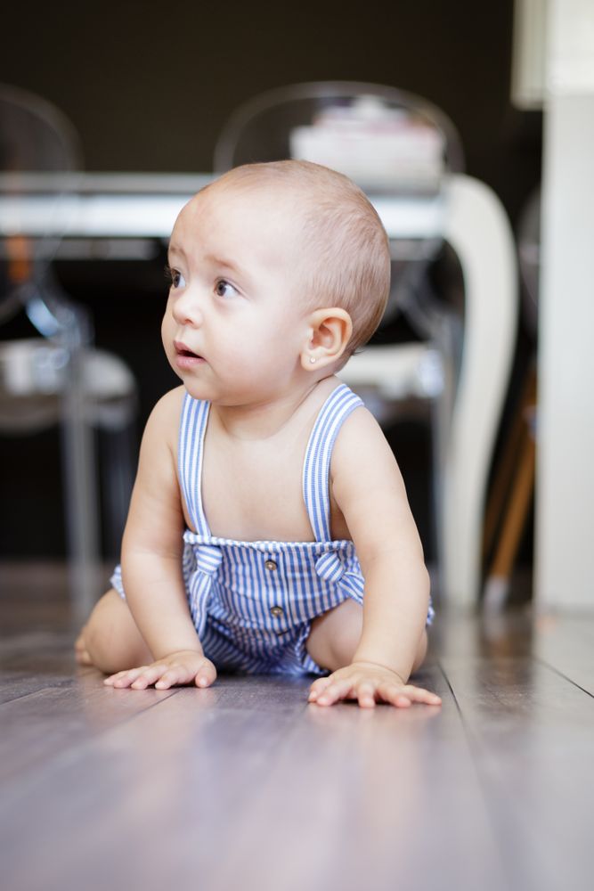Happy baby sitting on floor in kitchen