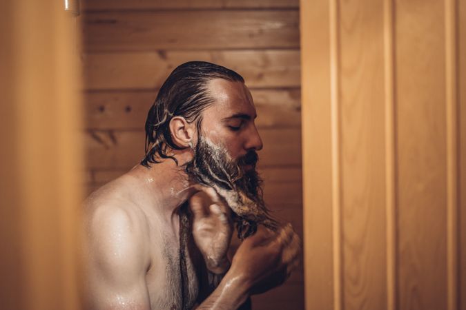 Man taking shower in wooden bathroom