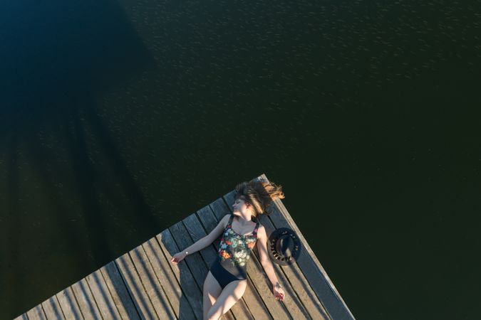 Young female lying down on pier on nature