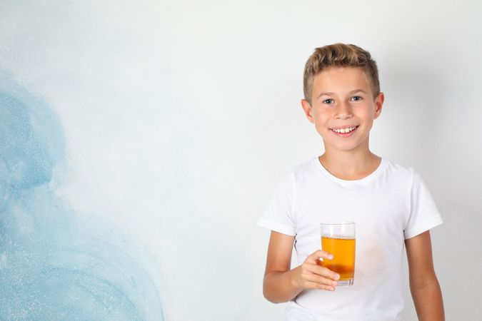 Smile boy with sweet cocktail against blank background