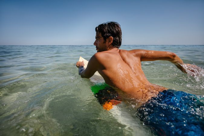 Young man drifting on surfboard in the ocean