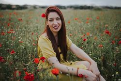 Woman sitting in field with poppies and daisies