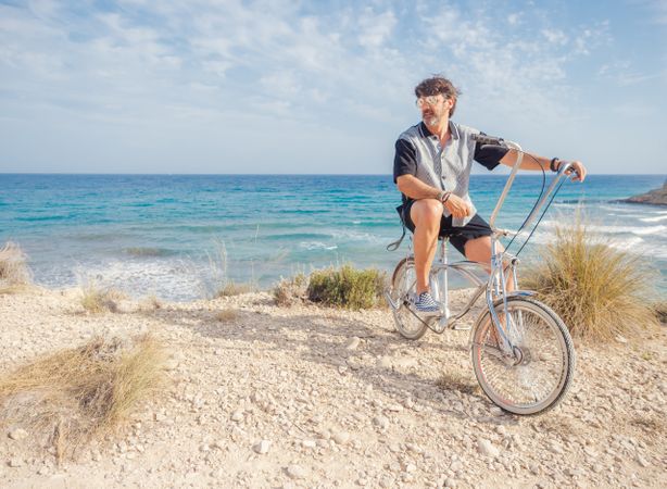 Man cycling on sandy beach hill