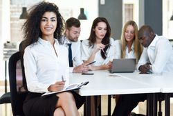 Curly haired businesswoman smiling in office looking at camera