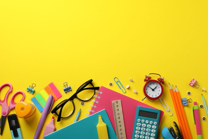 Flat lay of colorful stationary on yellow table