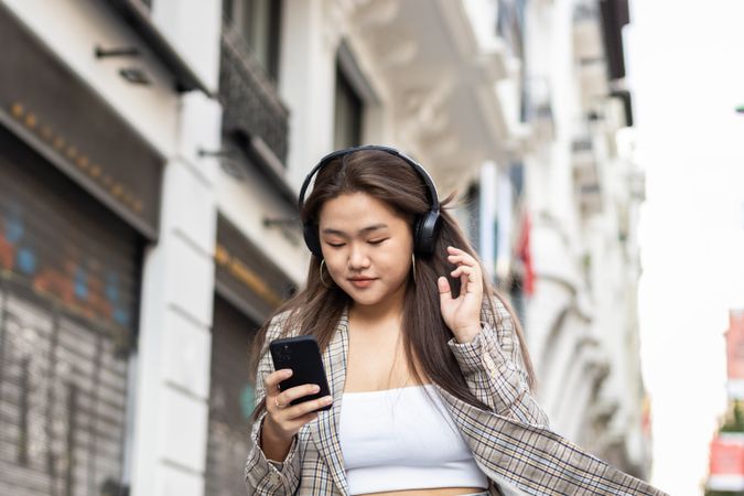 Young Asian woman listening to music with smartphone in the city