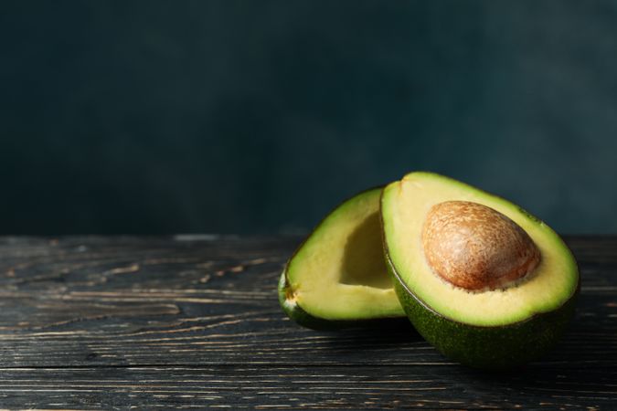 Ripe fresh avocado on wooden table, space for text