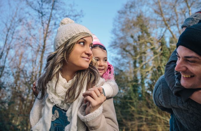 Happy mother giving daughter piggy back in forest