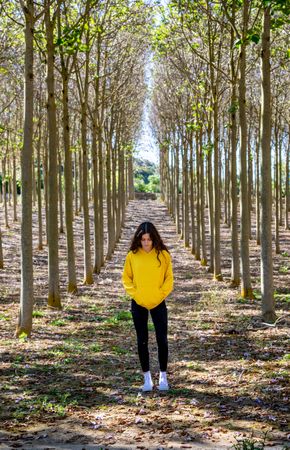 Fit teenage girl standing in forest dressed in yellow