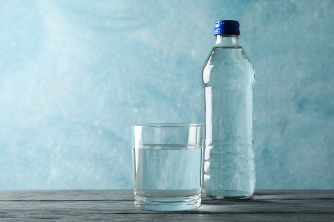 Glass of water with bottle in blue room