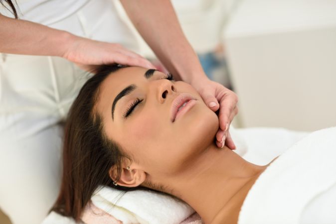 Arab female having face massaged in spa wellness center