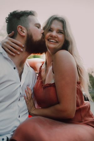 Loving couple sitting on car on road near forest