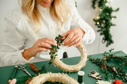 Woman decorating Christmas wreath at home