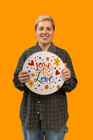 Happy person holding a colorful 'Love is Love' sign for LGBTQ Pride month