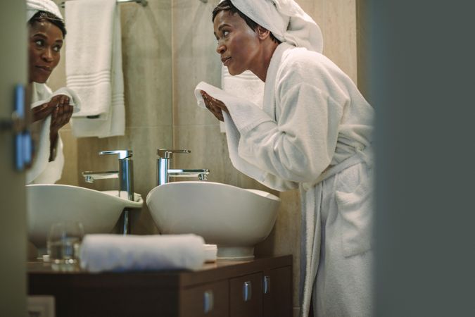 Female cleaning her face with towel in bathroom