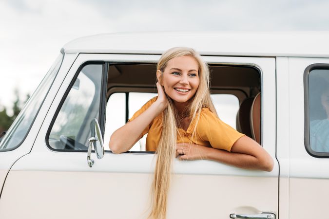 Woman leaning out of driver’s window of car with long blonde hair