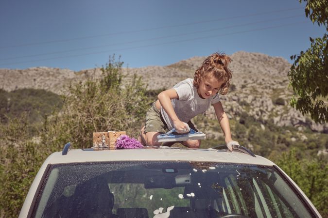 Boy washing car with window cleaning tool