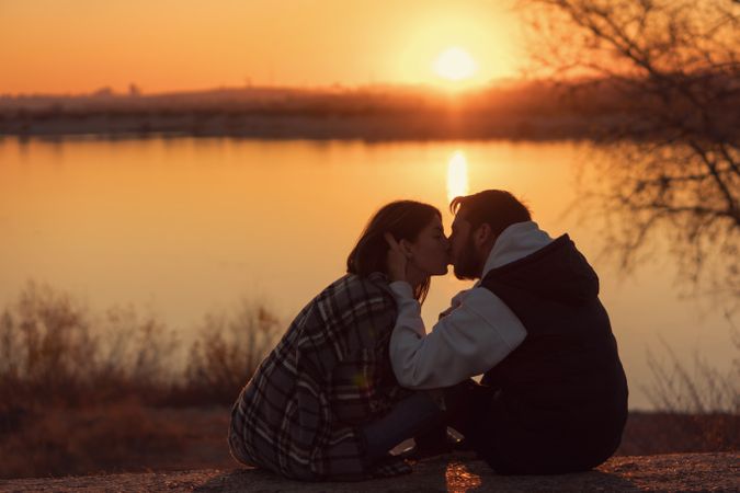 Couple sitting sunset lake