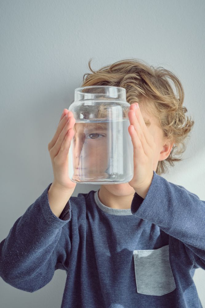 Kid covering face with jar of water