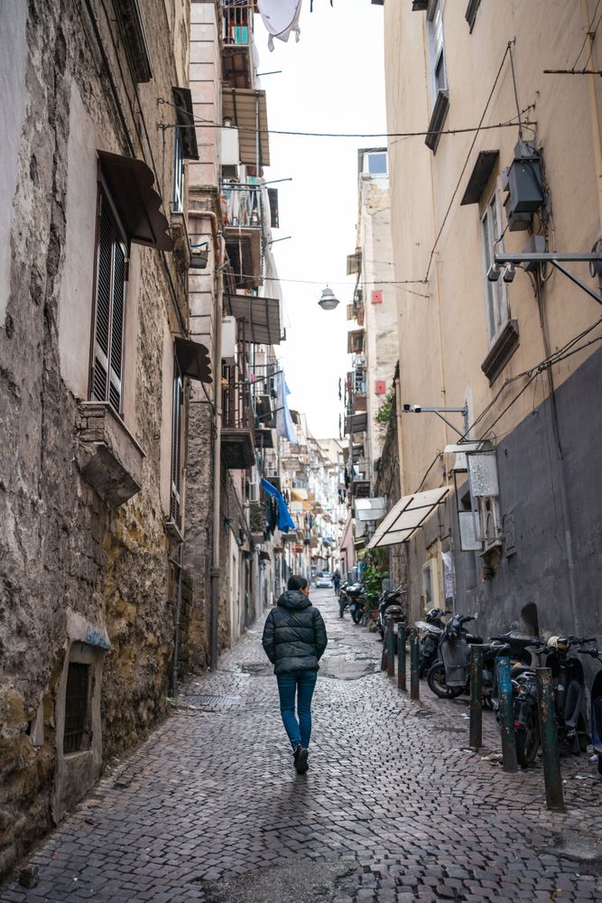 Anonymous female traveler in warm wear walking on narrow old street