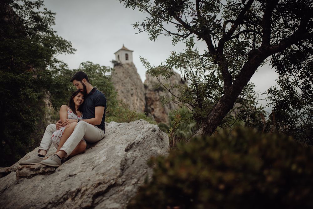 Romantic couple resting on rock surrounded with trees
