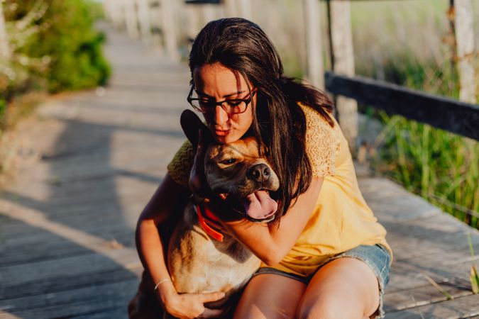 Happy adult woman hugging dog at countryside