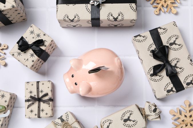 Piggy bank with cash and gift boxes on neutral background, top view