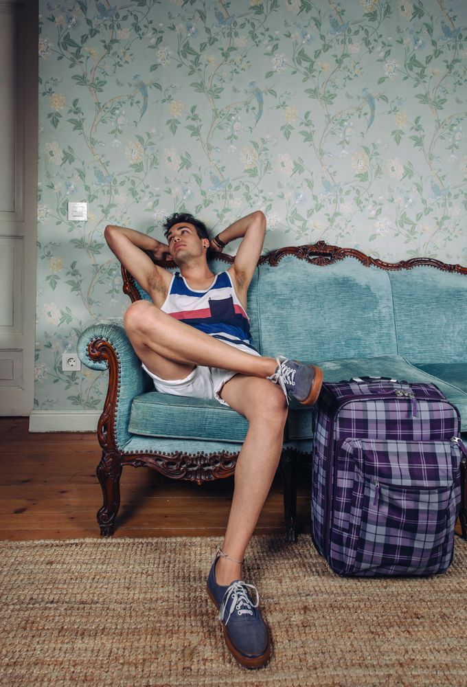 Man sits on sofa with suitcase