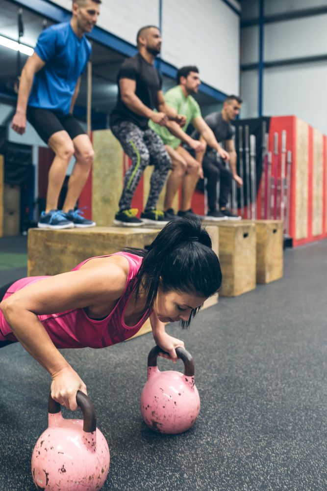 Sportswoman doing push-ups with kettlebells